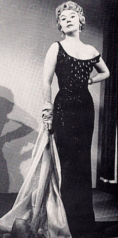 an old fashion photo of a woman in a black evening dress with pearls on it