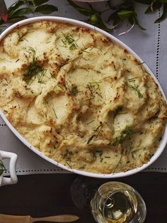 a casserole dish filled with potatoes and garnished with herbs