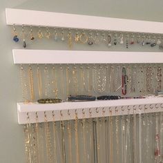 a white shelf filled with lots of necklaces and bracelets hanging from it's sides