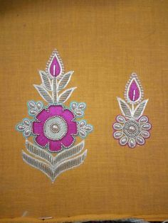 two embroidered designs on an orange cloth, one with pink and white flowers in the center