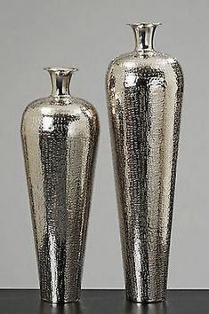 two shiny silver vases sitting next to each other