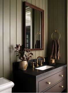 a bathroom sink sitting under a mirror next to a wooden cabinet and wall mounted faucet