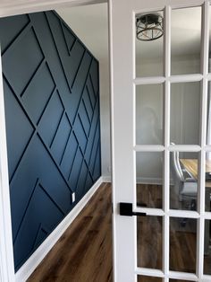 an empty room with blue walls and wood floors in the center is seen through glass doors