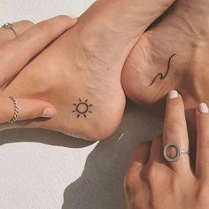 two people with tattoos on their feet holding each other's hands and touching the ground