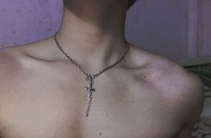 a woman wearing a necklace with a cross hanging from it's chest and the back of her neck