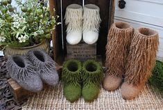 three pairs of boots are sitting on a mat next to some flowers and potted plants