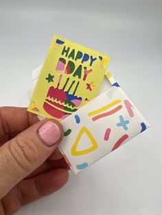 a hand holding a piece of paper with a happy birthday card on top of it