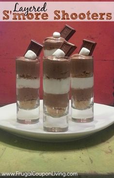 three shot glasses filled with chocolate and marshmallows on top of a plate