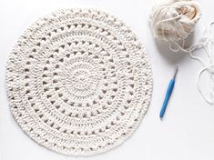 a crochet doily next to a ball of yarn and a knitting needle