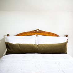 a bed with white sheets and green pillows