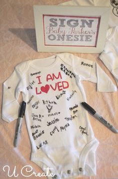 a baby's bodysuit with writing on it next to a sign that says i am loved