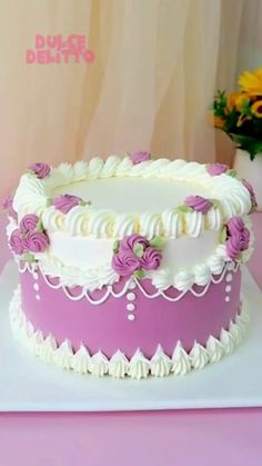 there is a large cake with white frosting and pink flowers on it's side