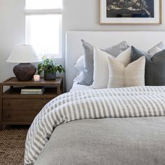 a bedroom with a bed, night stand and lamp on the side table in front of it