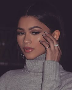 a close up of a person holding a cell phone to her ear and wearing a turtle neck sweater