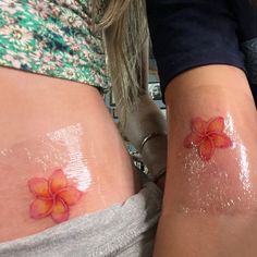 two women with tattoos on their stomachs and one has a red flower painted on the side