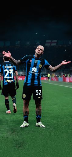 two soccer players standing on the field with their arms out and one is holding his hands out