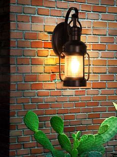 a light that is on the side of a brick wall next to a potted plant