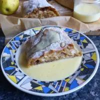 a piece of pie sitting on top of a blue and white plate next to an apple