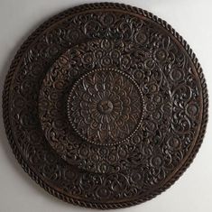 an ornately carved wooden plate on a white wall with a circular design in the center