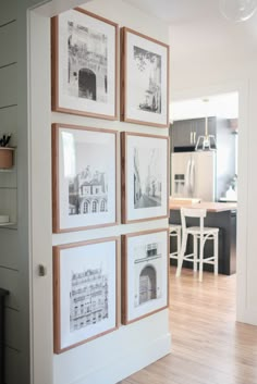 four framed photographs hang on the wall above a kitchen table and chairs in front of an open doorway