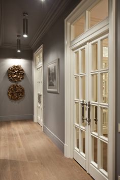 an empty hallway with white doors and wood flooring on either side of the room