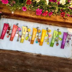 a bunch of different colored items are on a white cloth next to flowers and a wooden bench