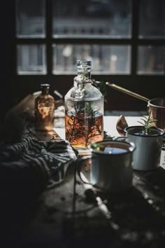 a glass bottle filled with liquid sitting on top of a table next to pots and pans