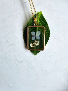 a necklace with four leaves and flowers in the center on a gold plated chain