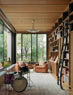 a living room filled with furniture and a drum set in front of a large window