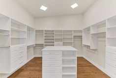 an empty closet with white shelves and drawers