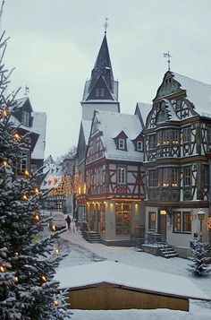 a christmas tree in front of a building with lights on it and a clock tower