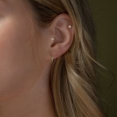 a close up of a woman's ear with two diamond studs on it