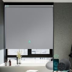 a bathroom with a window covered in grey roller shades next to a bathtub and chair