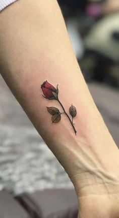 a small rose tattoo on the left inner forearm and foot, with two buds coming out of it