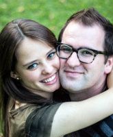 a man and woman hugging each other in the grass