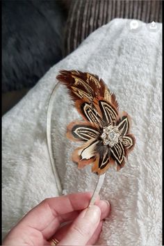 a person is holding a hair band with a flower on it and some feathers in the middle