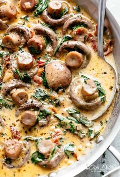 a pan filled with mushrooms and spinach on top of a table next to a fork