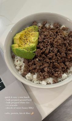 a bowl filled with rice, meat and avocado on top of a laptop