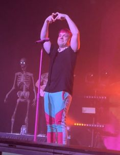 a man standing on top of a stage with his hands in the air and holding a microphone