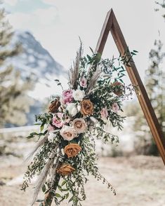 a wedding arch decorated with flowers and greenery in front of a snowy mountain backdrop