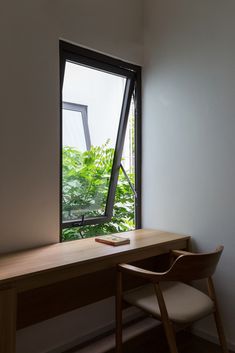 a desk with a book on it next to a window that looks out onto the outdoors