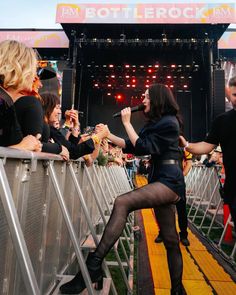 a woman in black dress standing on stage with crowd