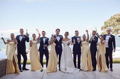 a group of people standing next to each other posing for a photo in front of the ocean