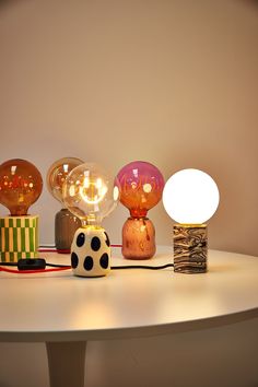 a table with three different colored lamps on top of it and a dice next to the lamp