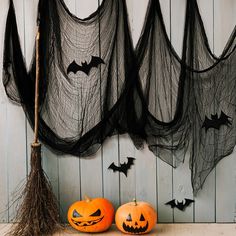 two pumpkins sitting next to each other with bats hanging from the ceiling behind them