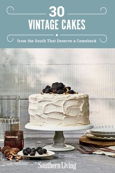 a cake with white frosting and blackberries sitting on top of a wooden table