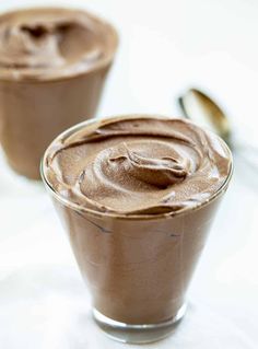 two glasses filled with chocolate pudding on top of a table