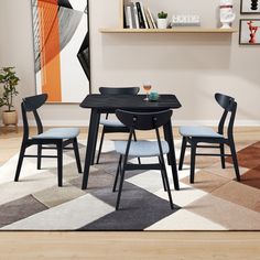 a black table with four chairs and a white rug in front of it on top of a hard wood floor