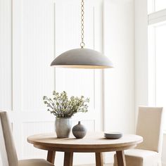 a dining room table with two chairs and a potted plant on the table in front of it