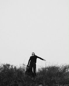 a man standing on top of a grass covered hillside